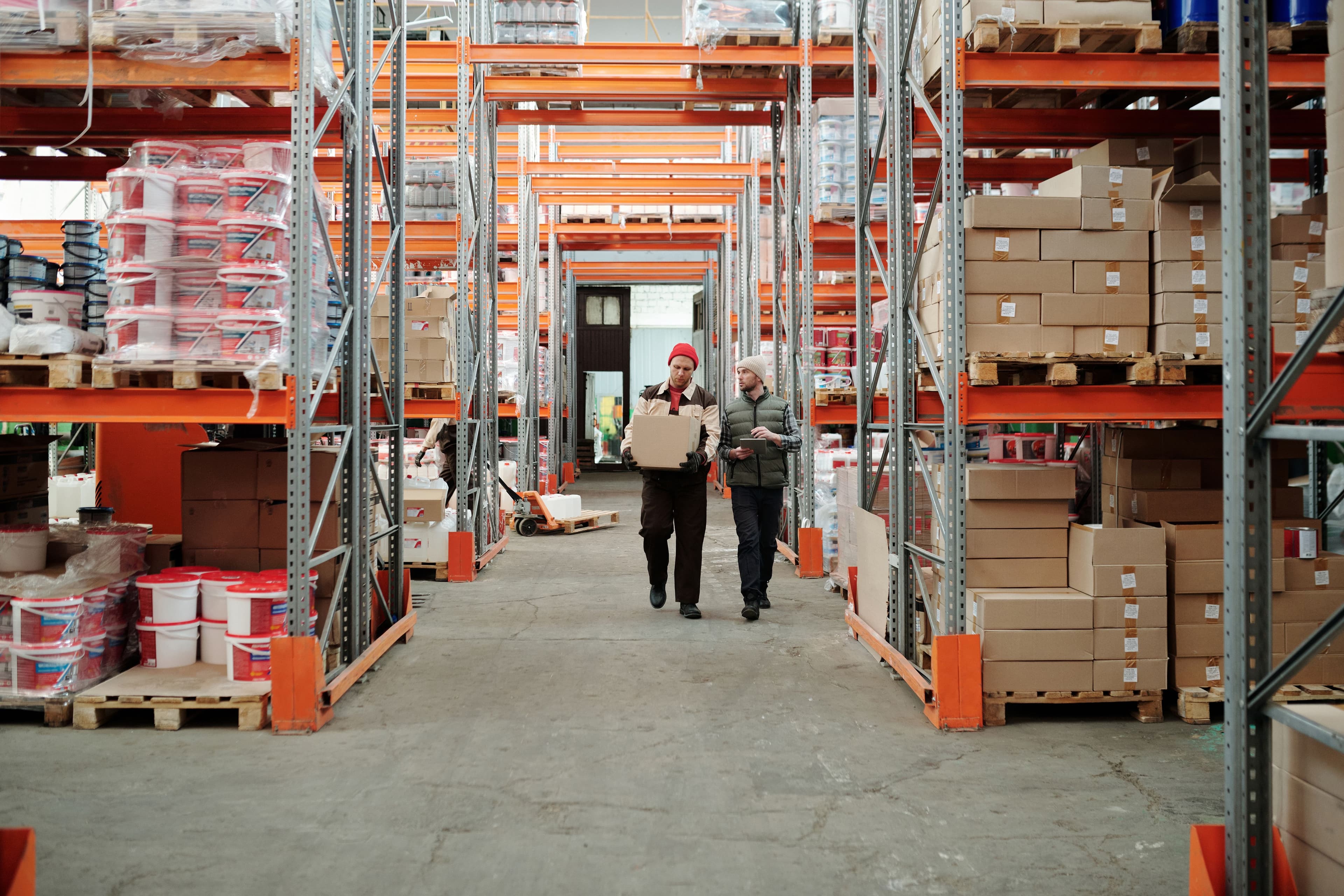 Two SPS warehouse workers carrying stock down an aisle of racking
